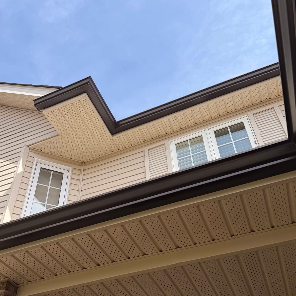 Brown seamless eavestrough and downspout trim along the roofline of a home with tan siding in the London, Ontario area