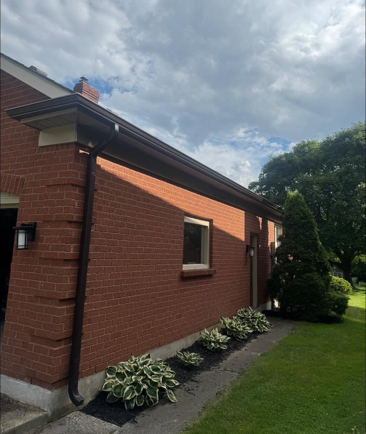 Dark brown seamless eavestrough and downspout on a red brick bungalow in the London, Ontario area