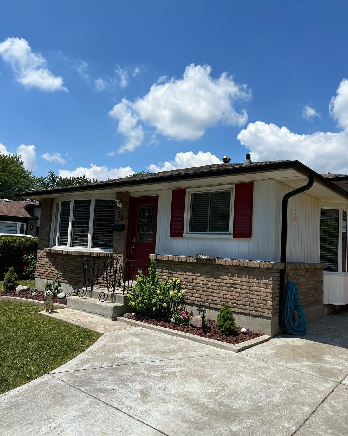Black seamless eavestrough and downspout on a brick and white-sided bungalow with red shutters in the London, Ontario area