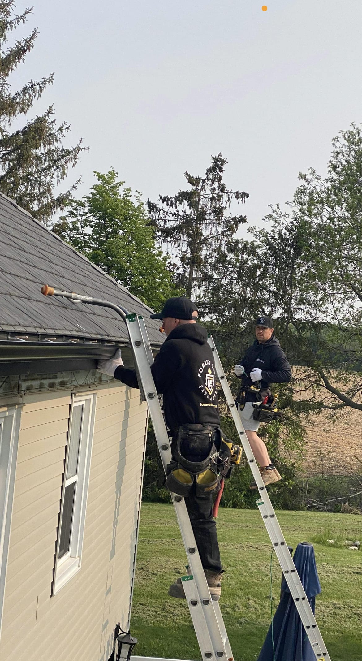 Forest City Eavestrough crew on ladders installing seamless eavestrough on a home in the London, Ontario area