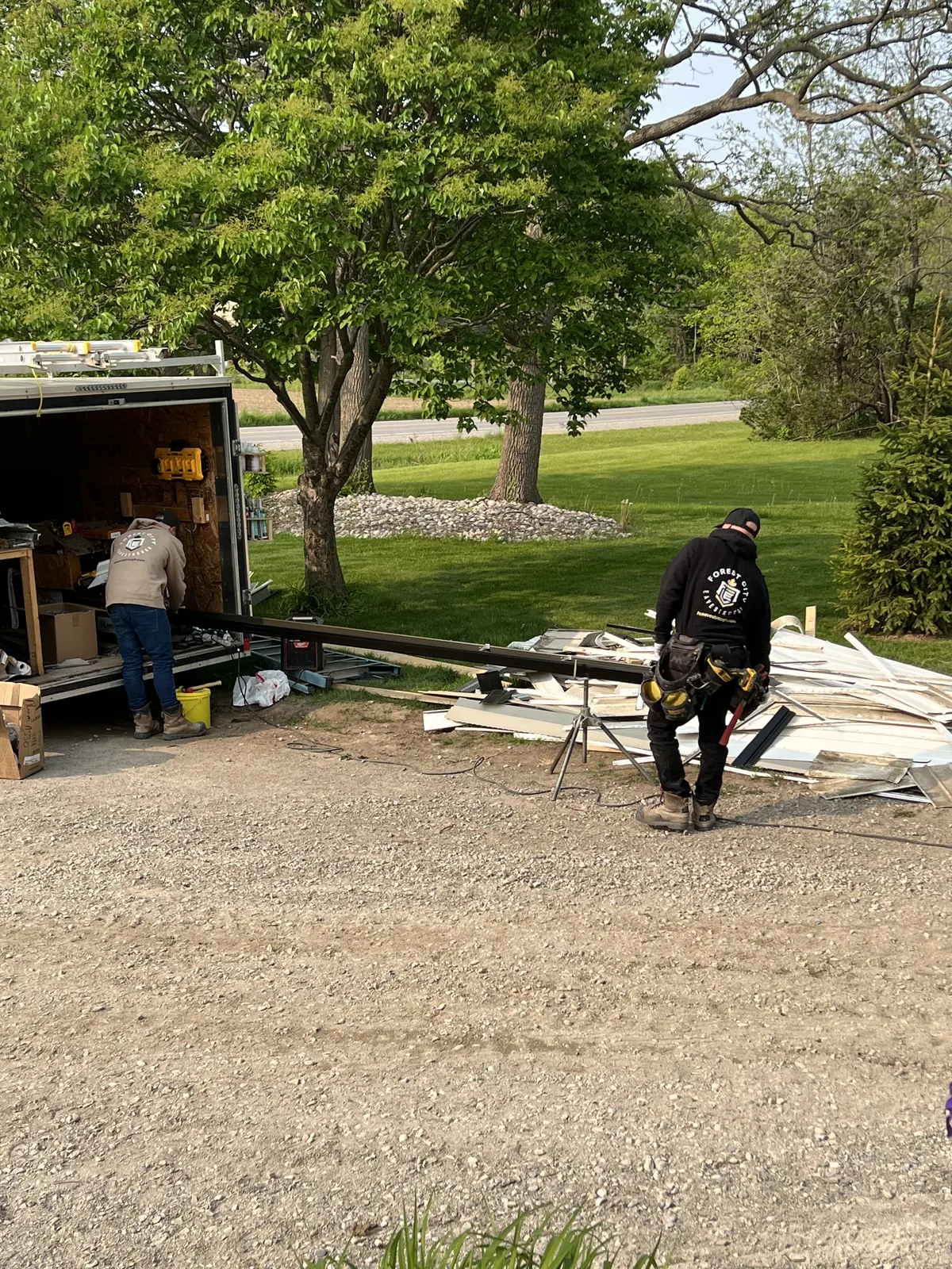 Forest City Eavestrough crew running black seamless eavestrough through a gutter machine at their trailer in the London, Ontario area