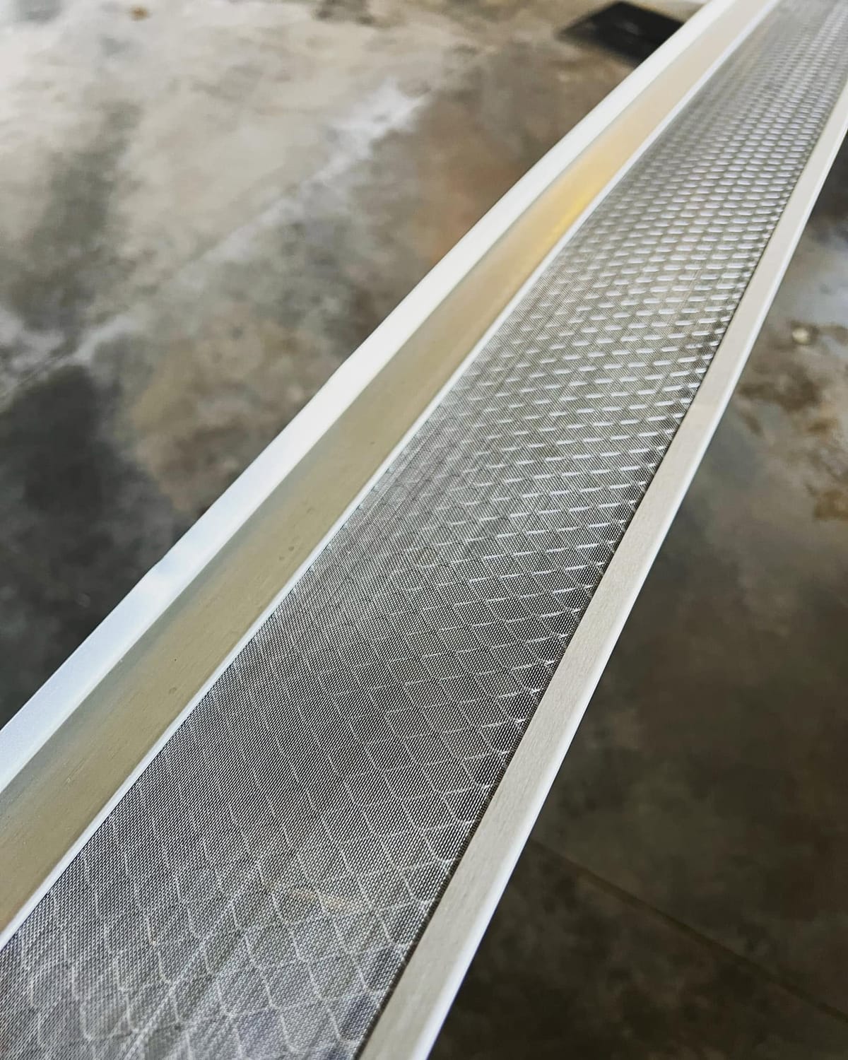 White seamless eavestrough with a diamond-pattern mesh gutter guards section laid out in the London, Ontario area
