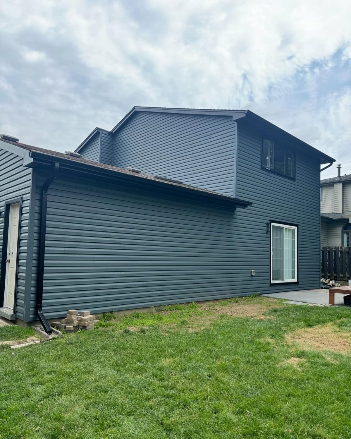 Blue-grey vinyl siding and black seamless eavestrough with a downspout on a two-storey home in the London, Ontario area