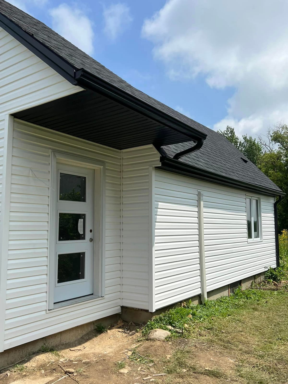 White vinyl siding with black seamless eavestrough, soffit and fascia on a new small home in the London, Ontario area