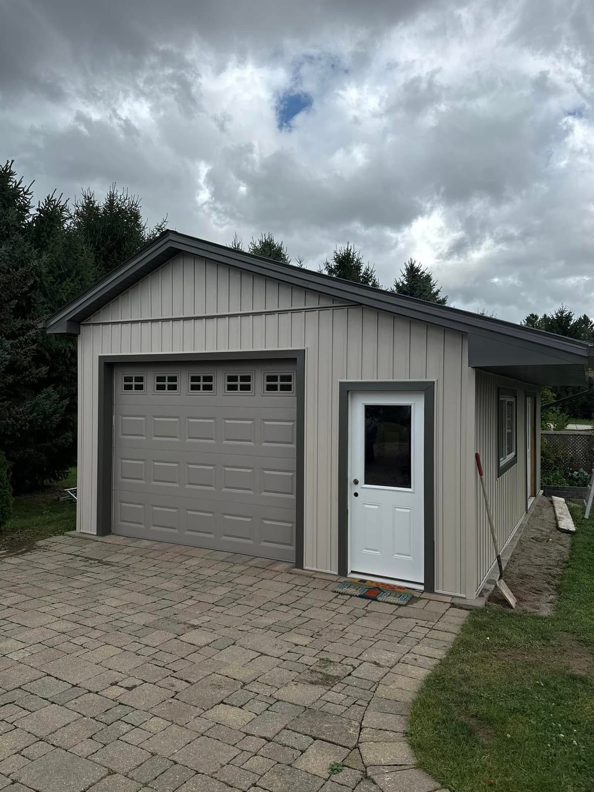 Detached garage with taupe vinyl siding, soffit and fascia, and a brown overhead door in the London, Ontario area