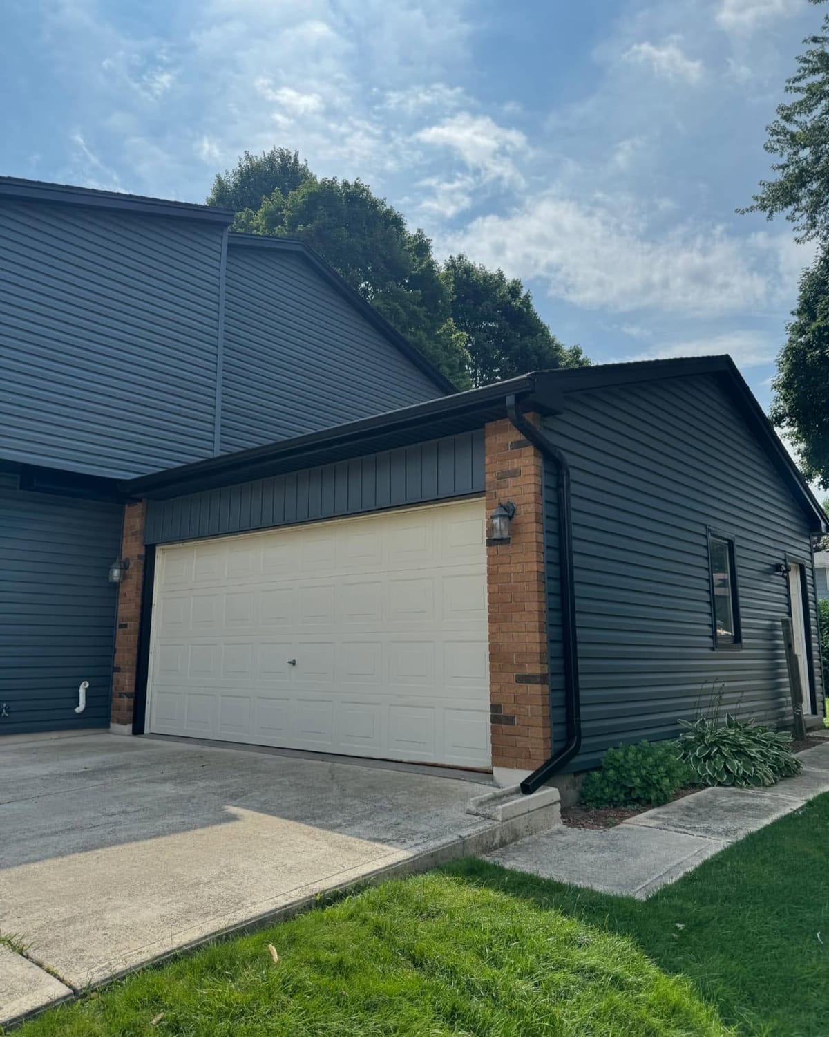 Charcoal vinyl siding and black seamless eavestrough on a garage with brick trim in the London, Ontario area