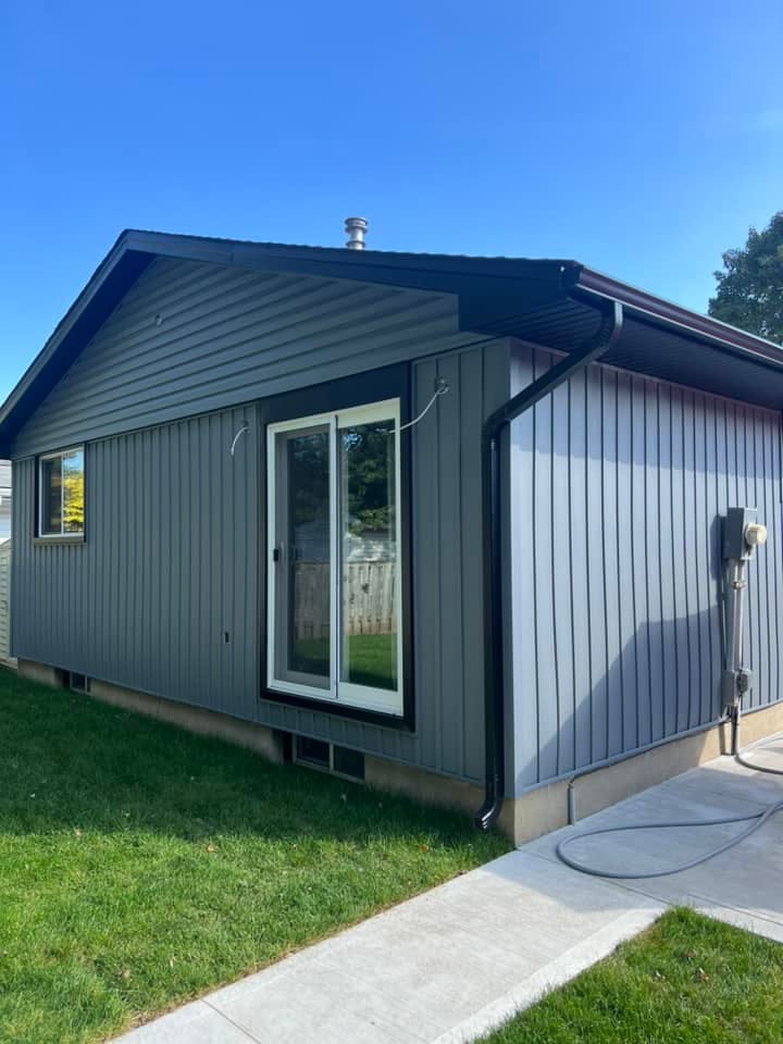 Grey vertical vinyl siding with black seamless eavestrough and downspout on a bungalow in the London, Ontario area