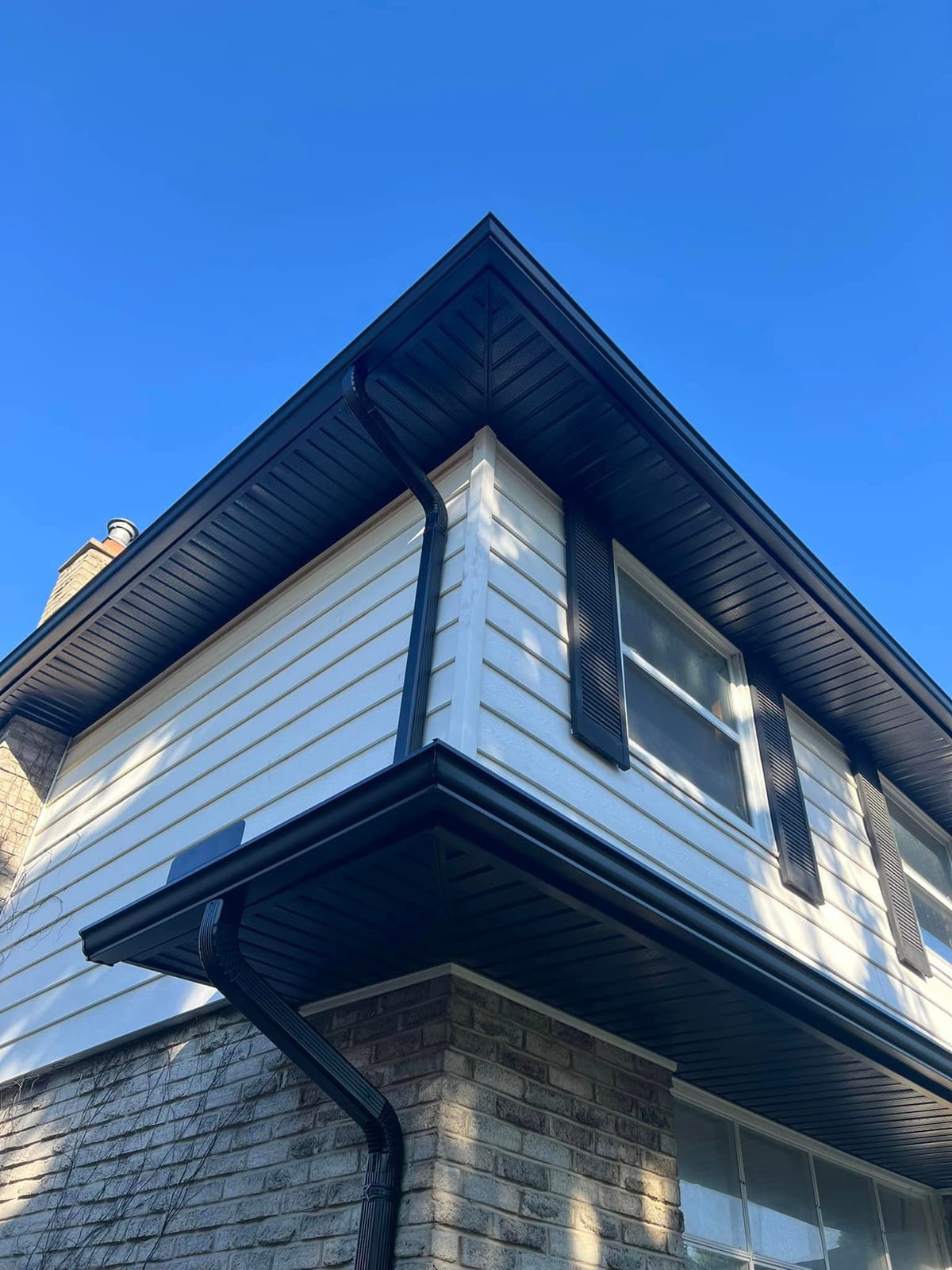 Black seamless eavestrough, downspouts, soffit and fascia on a home with white siding in the London, Ontario area