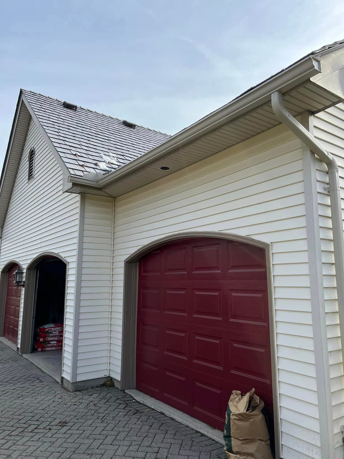 Beige seamless eavestrough and downspout on a white-sided home with a red garage door in the London, Ontario area