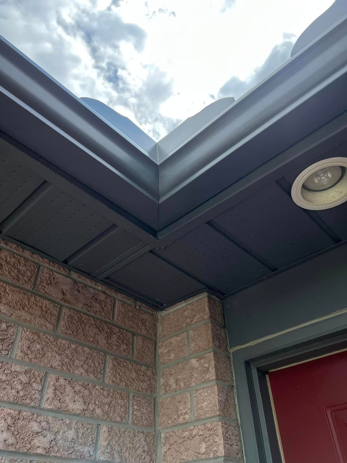 Close view of a grey seamless eavestrough corner with vented soffit and fascia beneath it, London, Ontario area