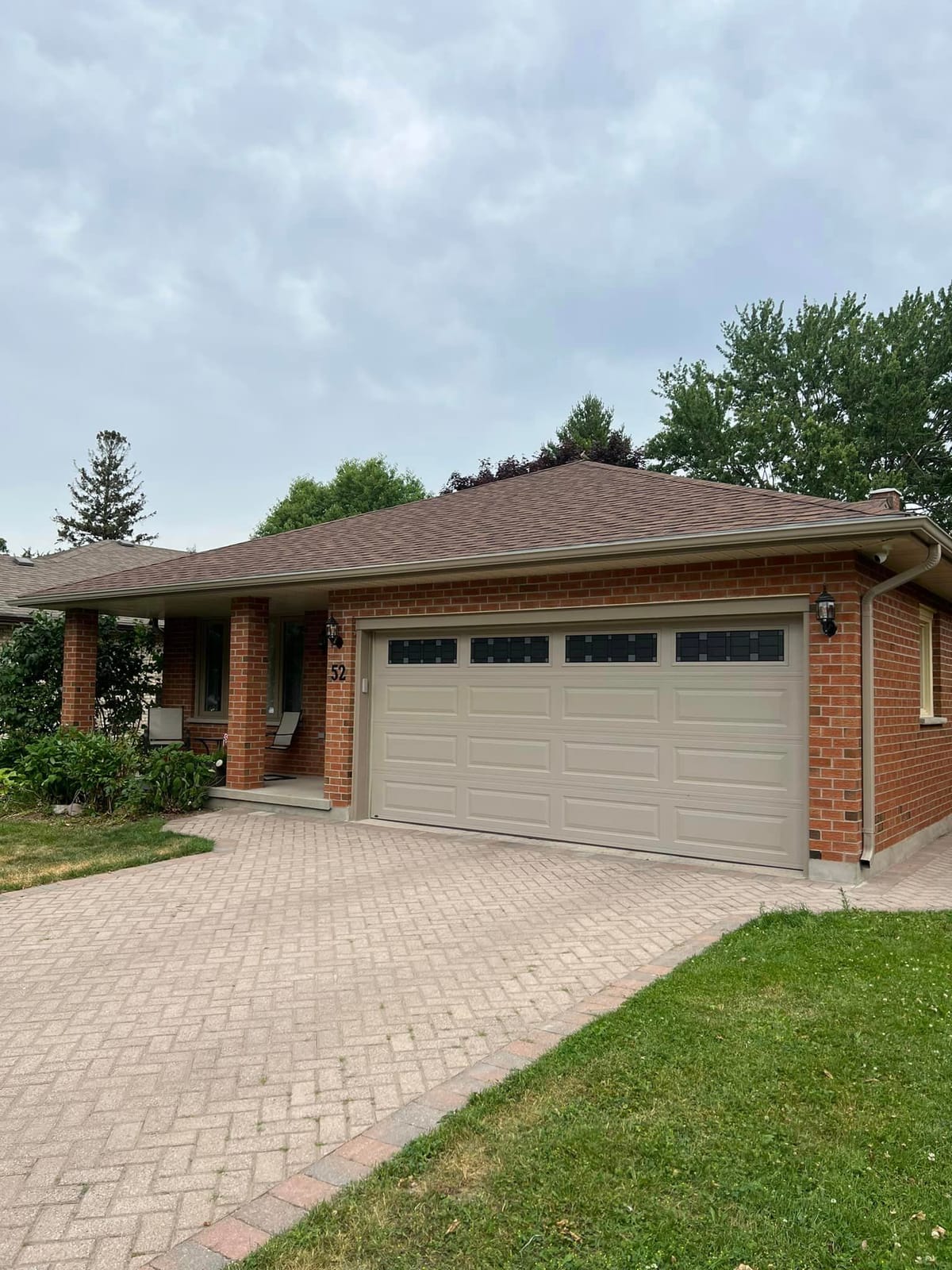 Seamless eavestrough and downspout on a red brick bungalow with a beige double garage door in the London, Ontario area