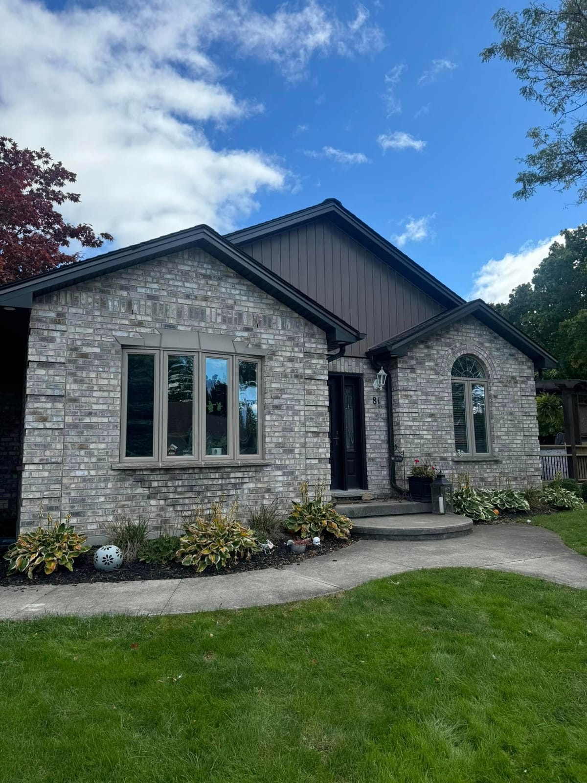 Dark vinyl siding with brown soffit, fascia and seamless eavestrough on a stone bungalow in the London, Ontario area