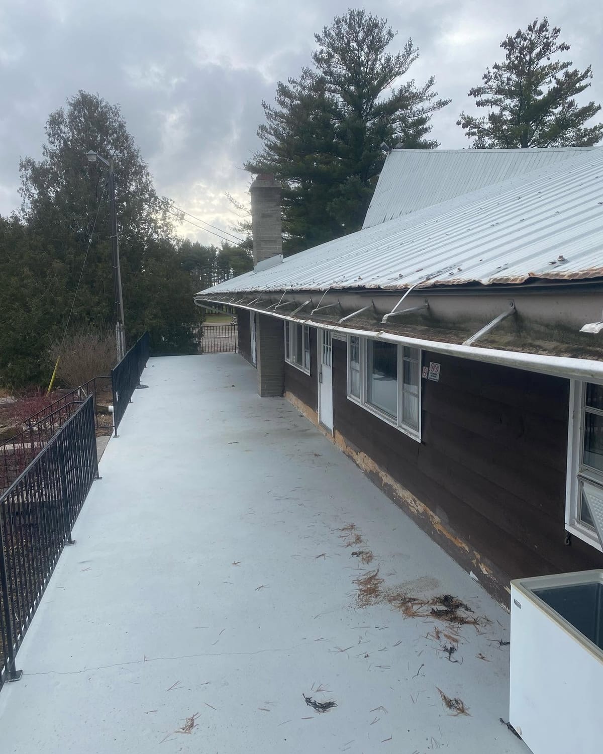 Sagging eavestrough with bent hangers along a building, before repair.