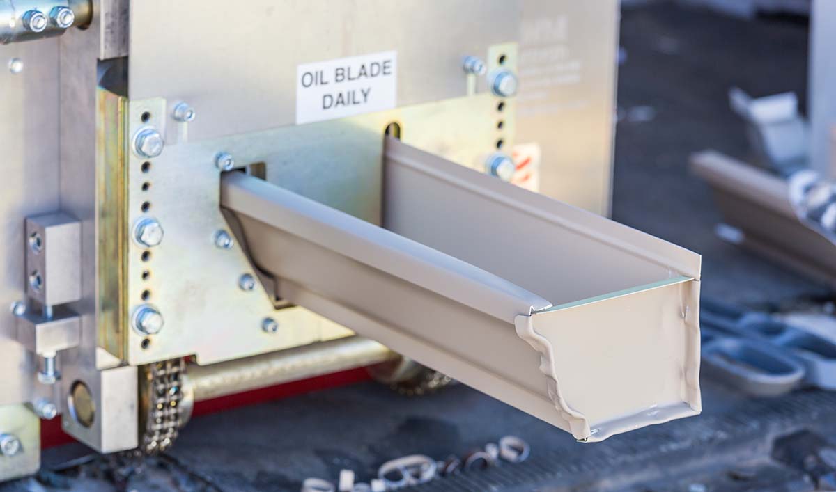 A length of seamless eavestrough coming out of the forming machine on site.
