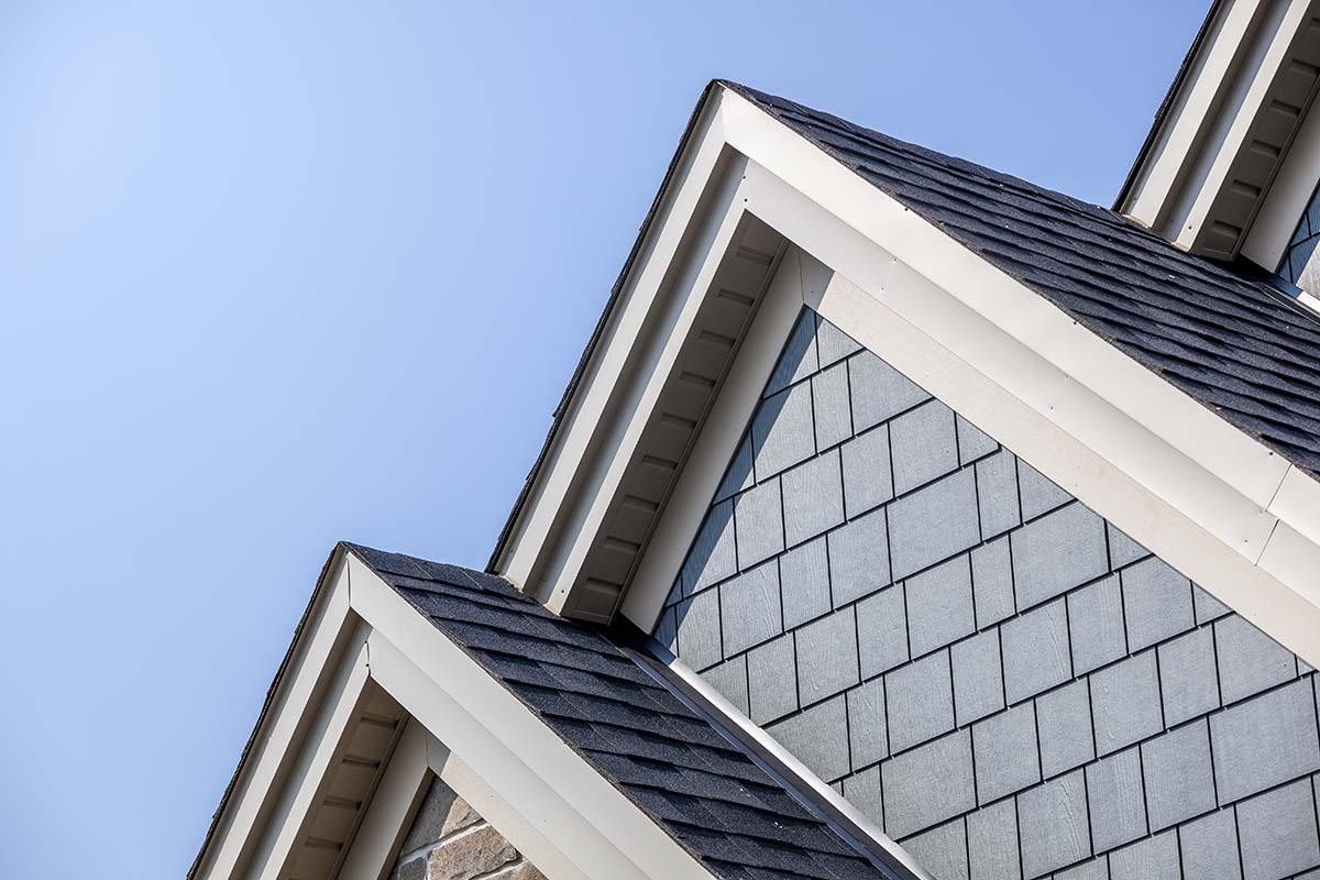 Two roof gables with white fascia and vented soffit against a blue sky.