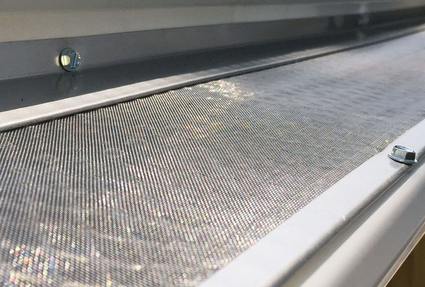 A fine mesh leaf guard fastened over an eavestrough.